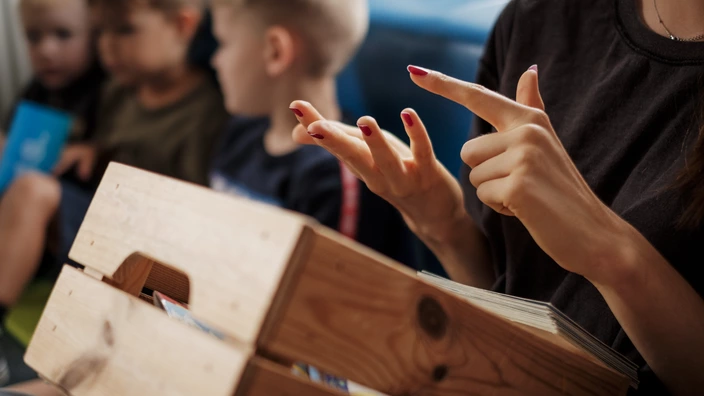 Ein Morgenkreis in einer CJD Kita. Eine Mitarbeiterin zählt mit den Fingern.